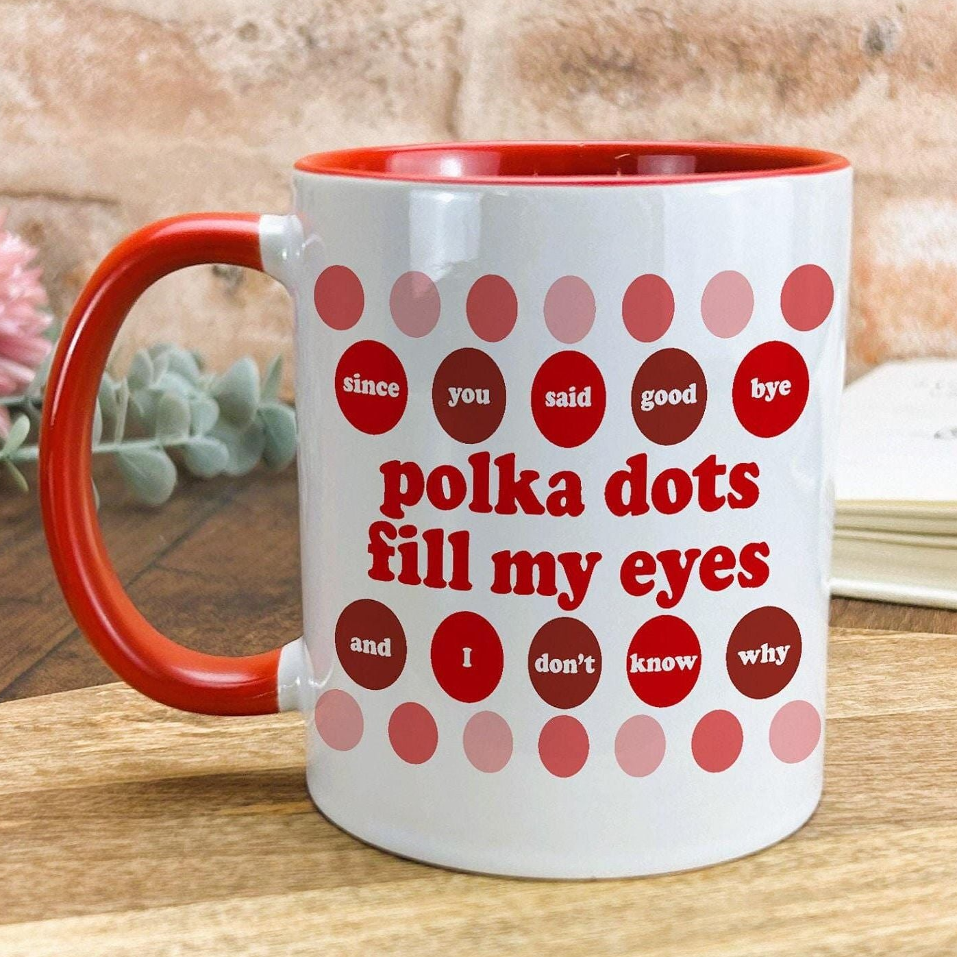 A white mug with a red handle, decorated with red polka dots and text that reads "Since you said good, I don't know why".