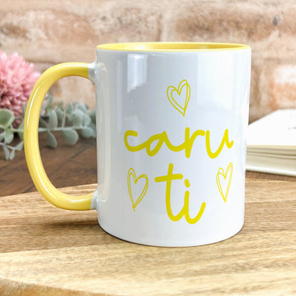 a yellow and white coffee mug sitting on top of a wooden table