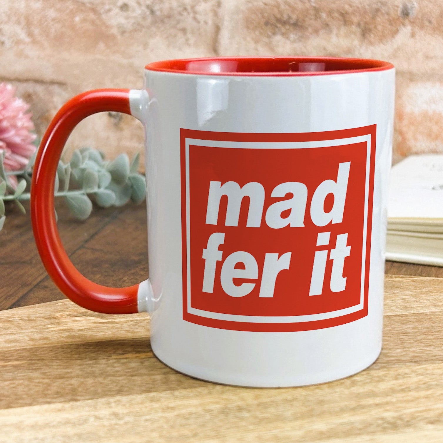 a red and white mug sitting on top of a wooden table