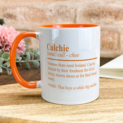 a white and orange coffee mug sitting on top of a wooden table