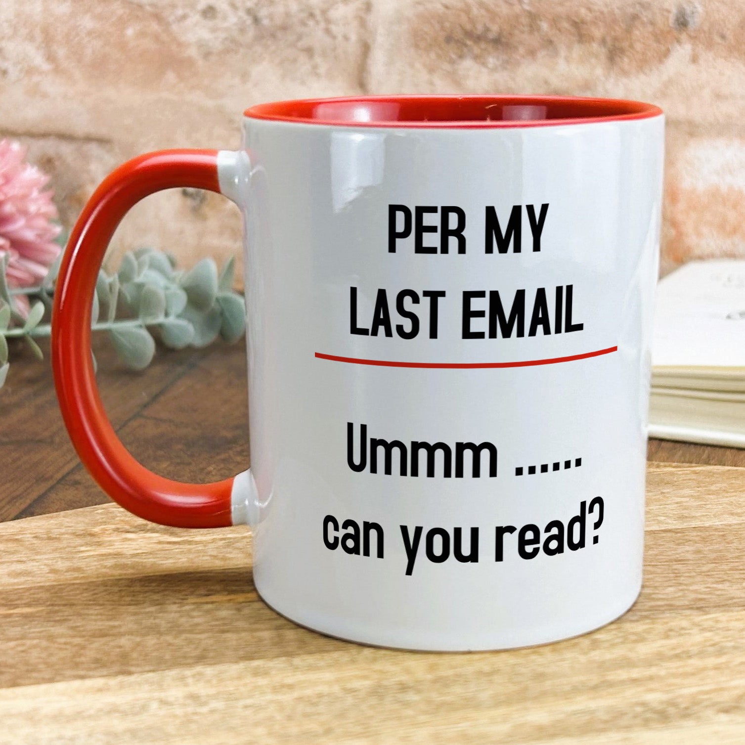 a red and white coffee mug sitting on top of a wooden table
