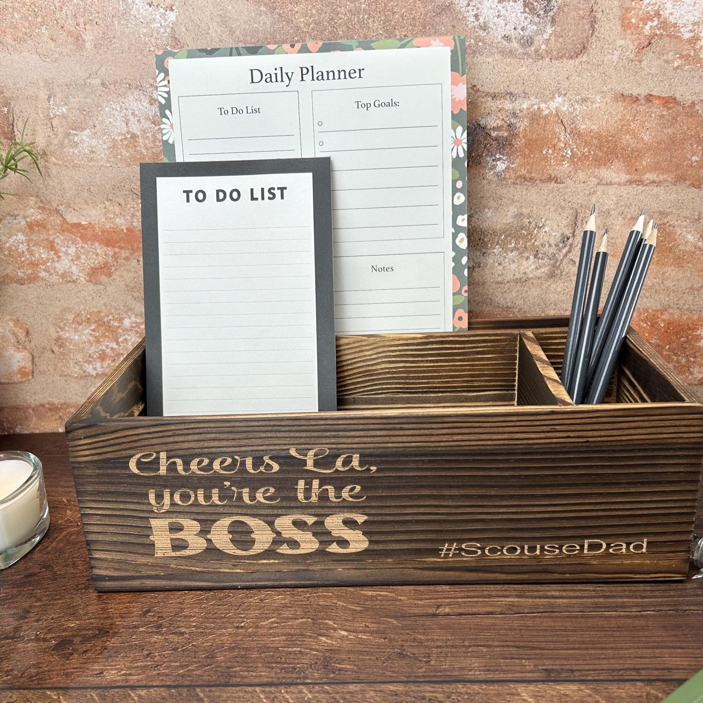 a desk with a notepad, pen holder and a candle