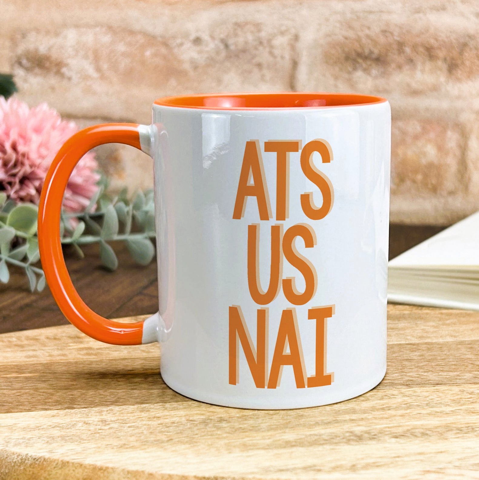 a white and orange coffee mug with the words ats us nai on it