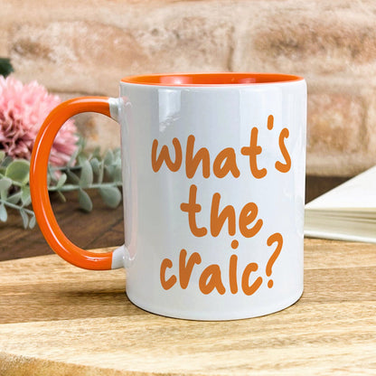 a white and orange coffee mug sitting on top of a wooden table