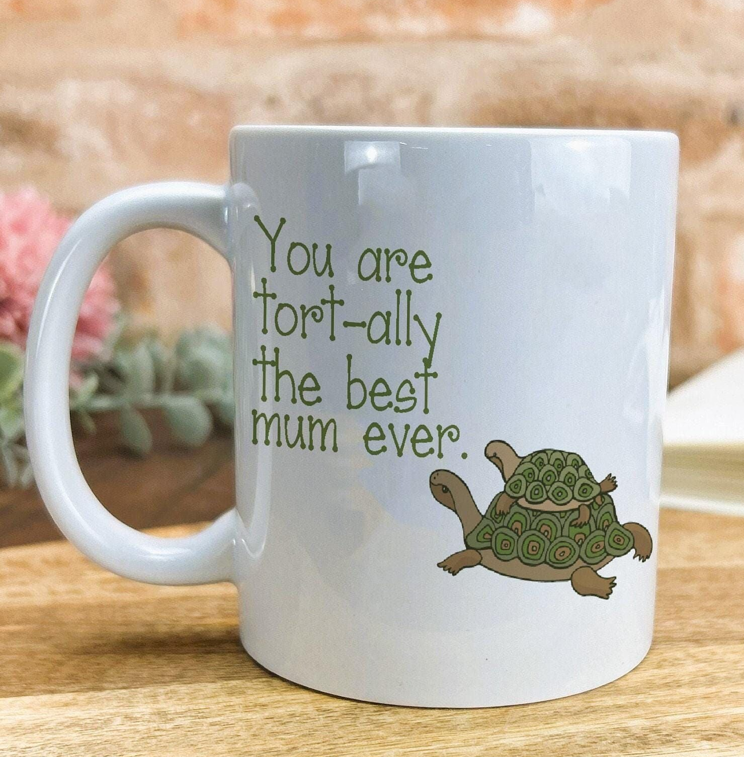 A white ceramic mug with a humorous text and an illustration of a turtle printed on it.
