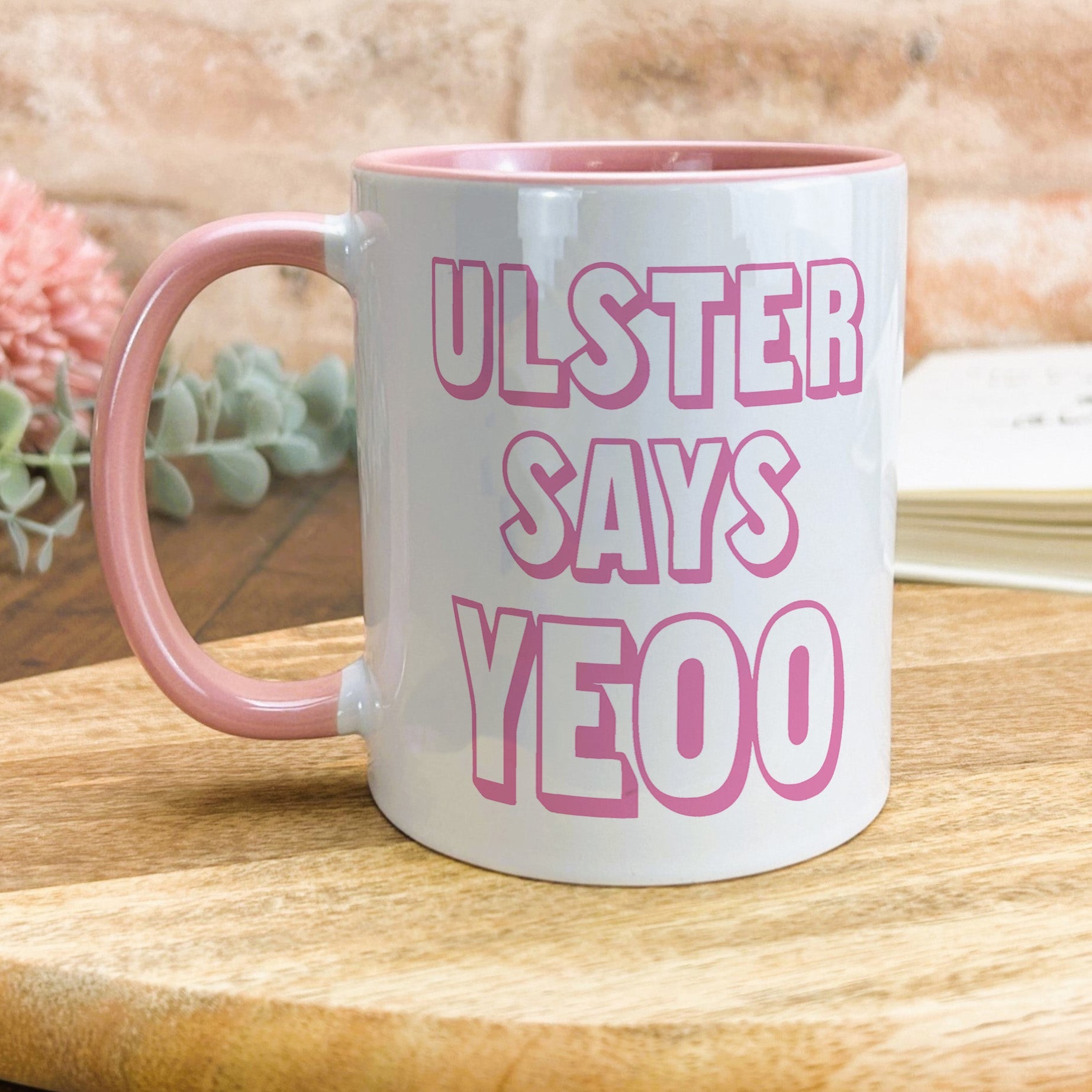 a pink and white coffee mug sitting on top of a wooden table