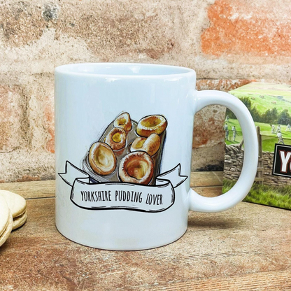 A white ceramic mug with a printed design of toasted bread and the text "Yorkshire Pudding Lover" printed on it.