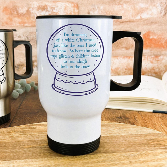A white travel mug with a blue design and text on it, placed on a wooden surface.