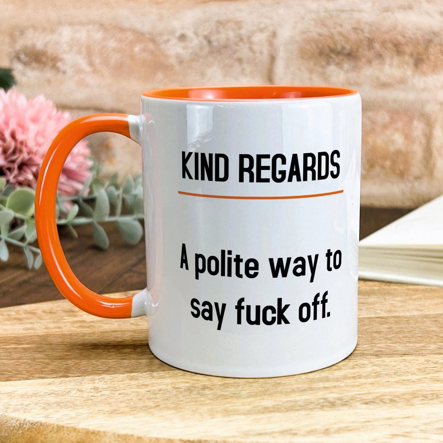 a white and orange coffee mug sitting on top of a wooden table