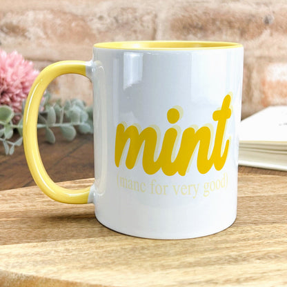 a yellow and white coffee mug sitting on top of a wooden table