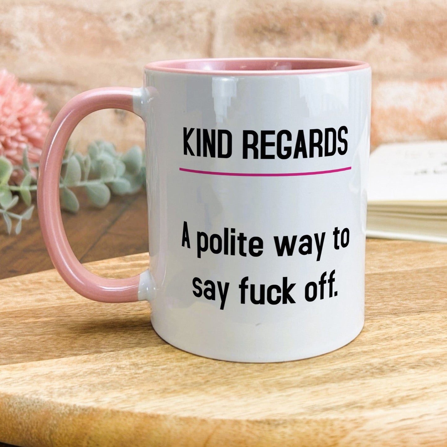 a pink and white coffee mug sitting on top of a wooden table