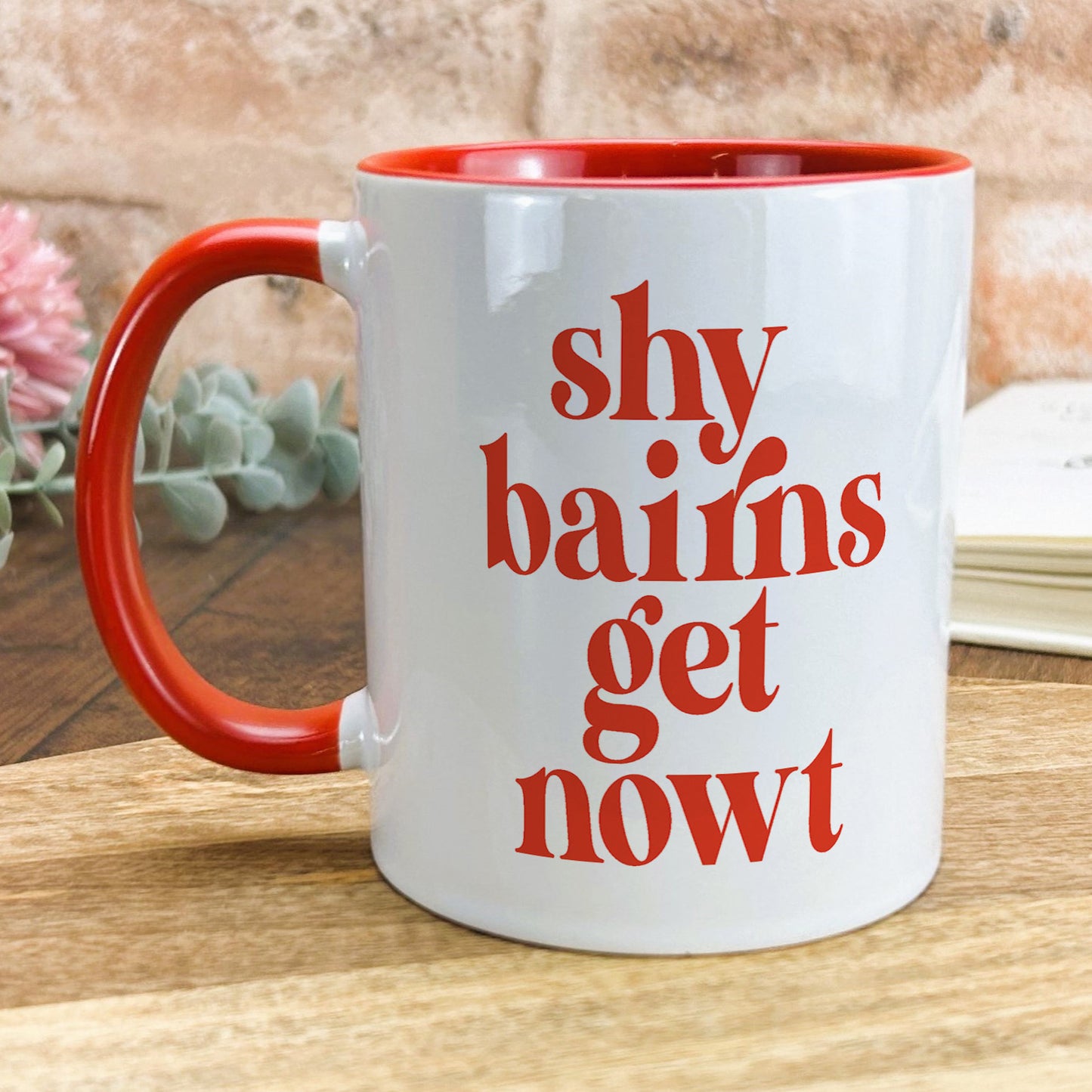 a red and white coffee mug sitting on top of a wooden table