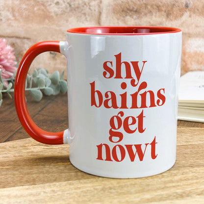 a red and white coffee mug sitting on top of a wooden table