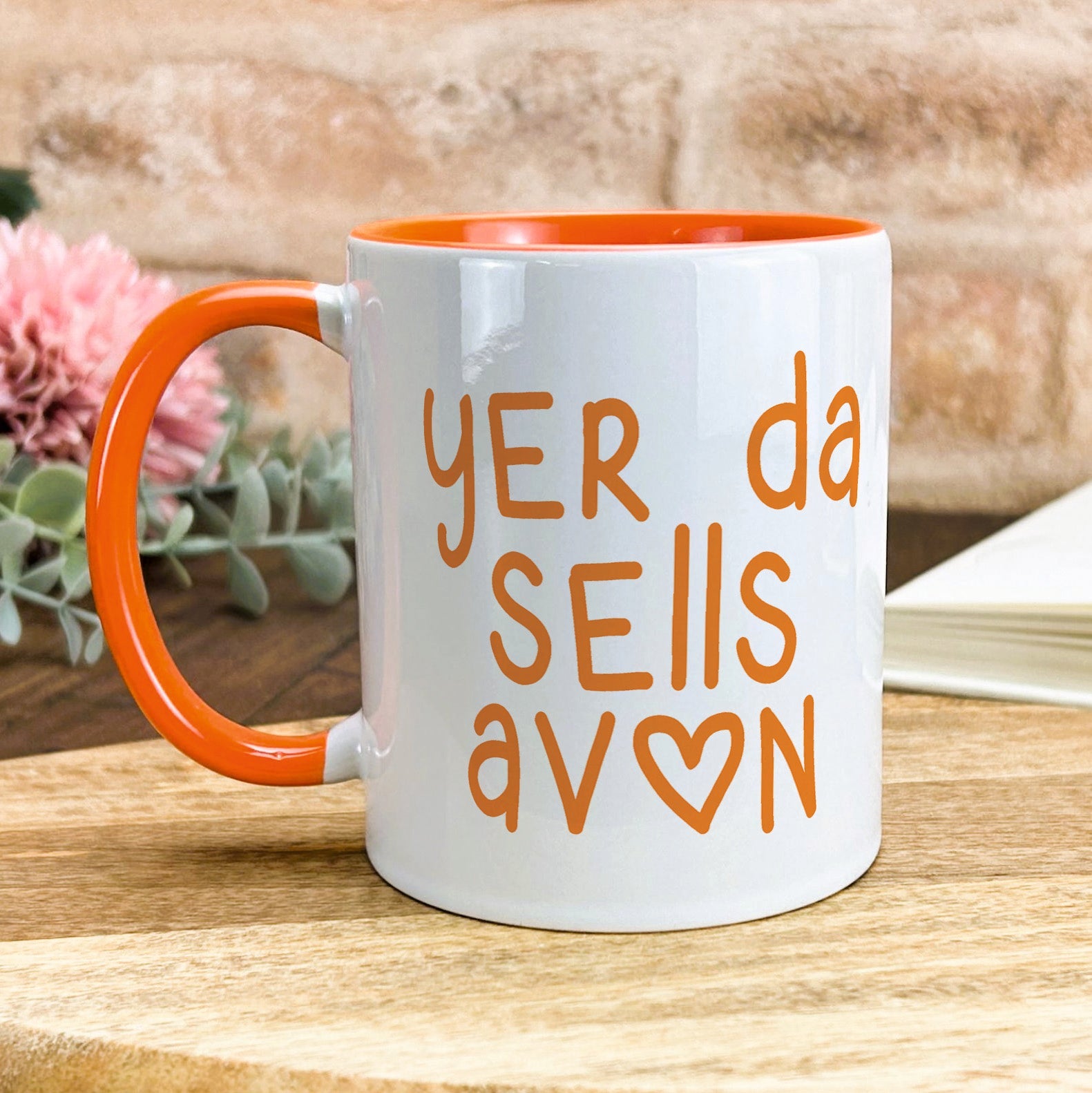 a white and orange coffee mug sitting on top of a wooden table