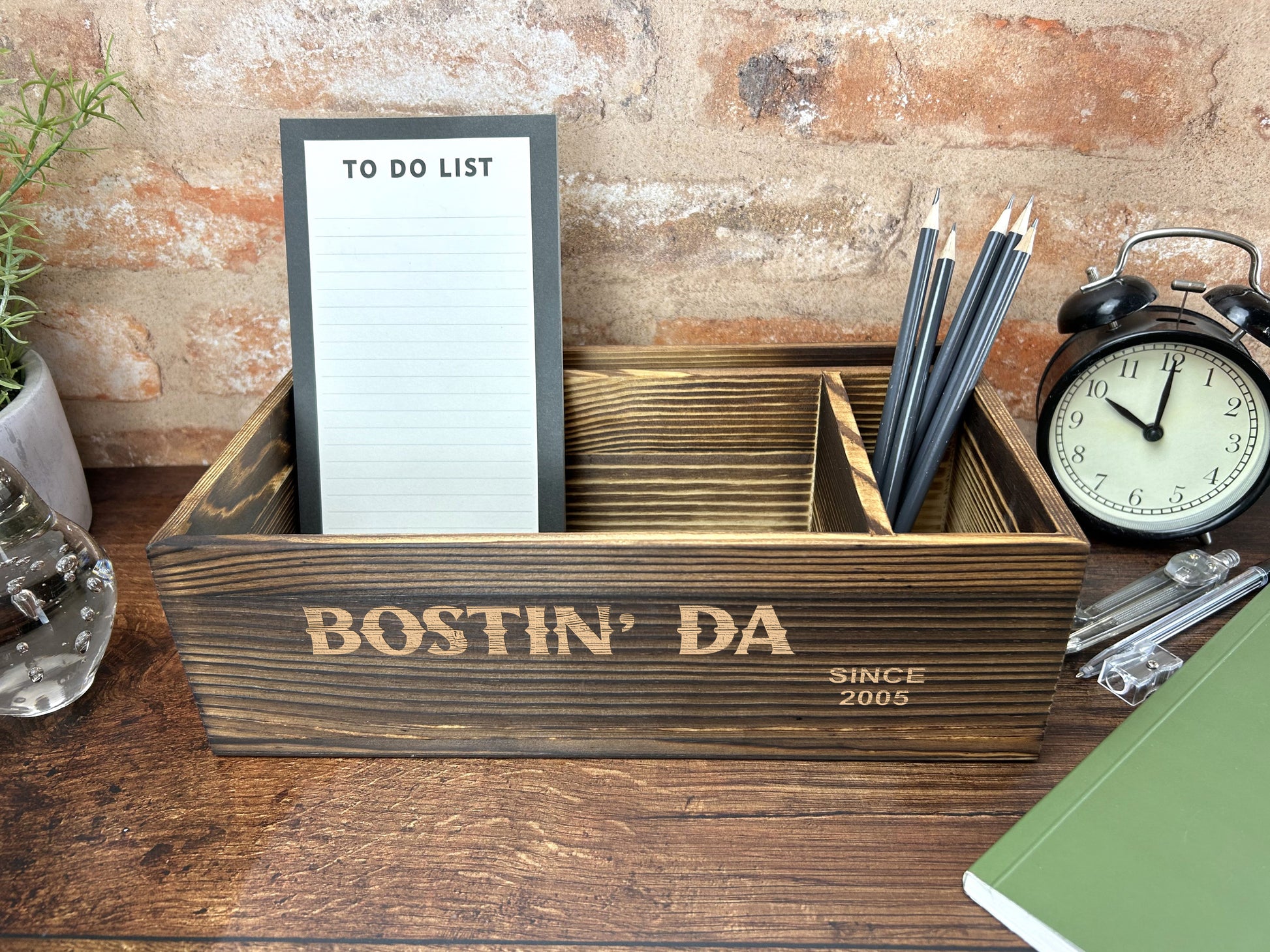 a desk with a clock, notepad and pen holder