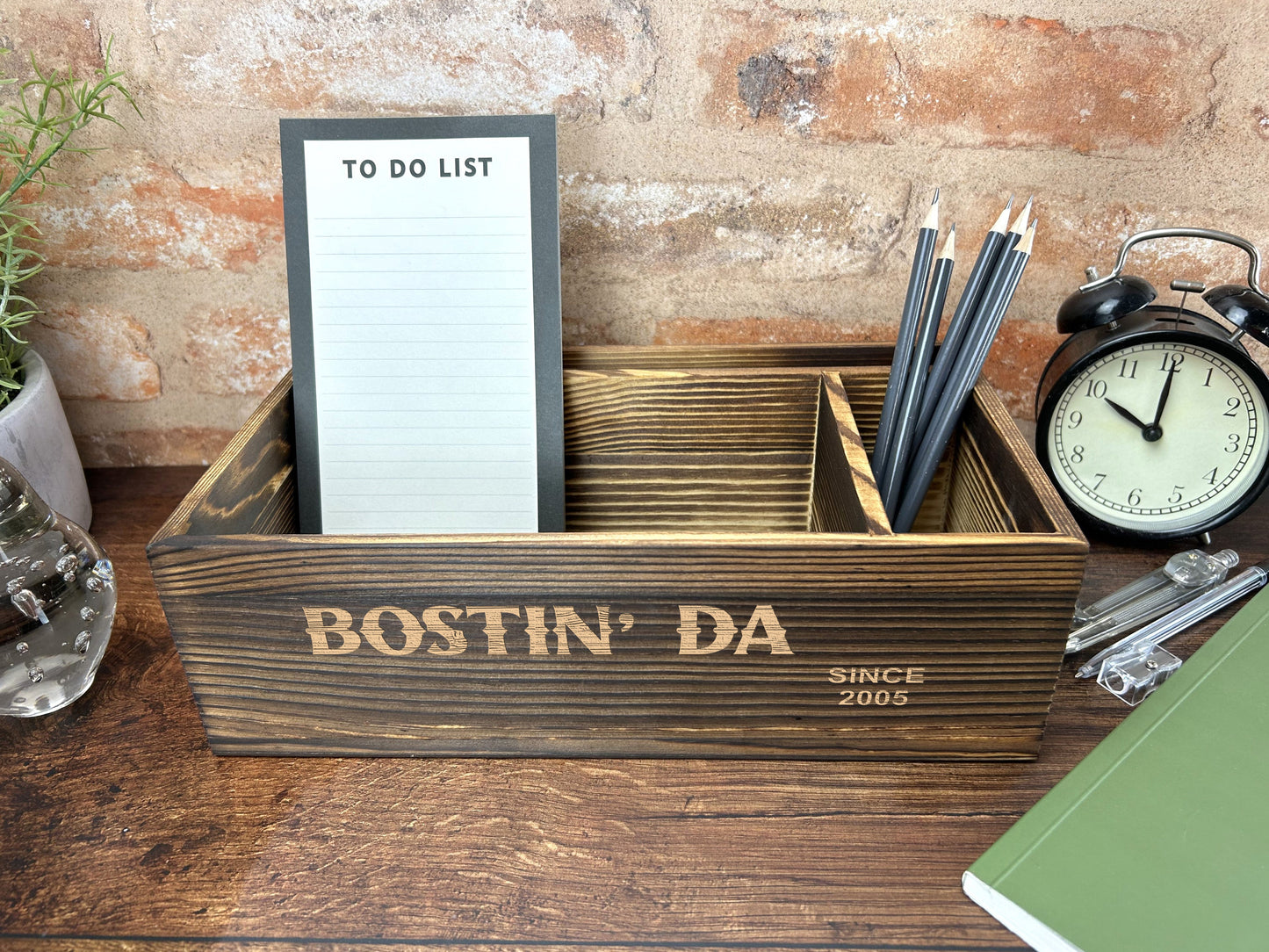a desk with a clock, notepad and pen holder