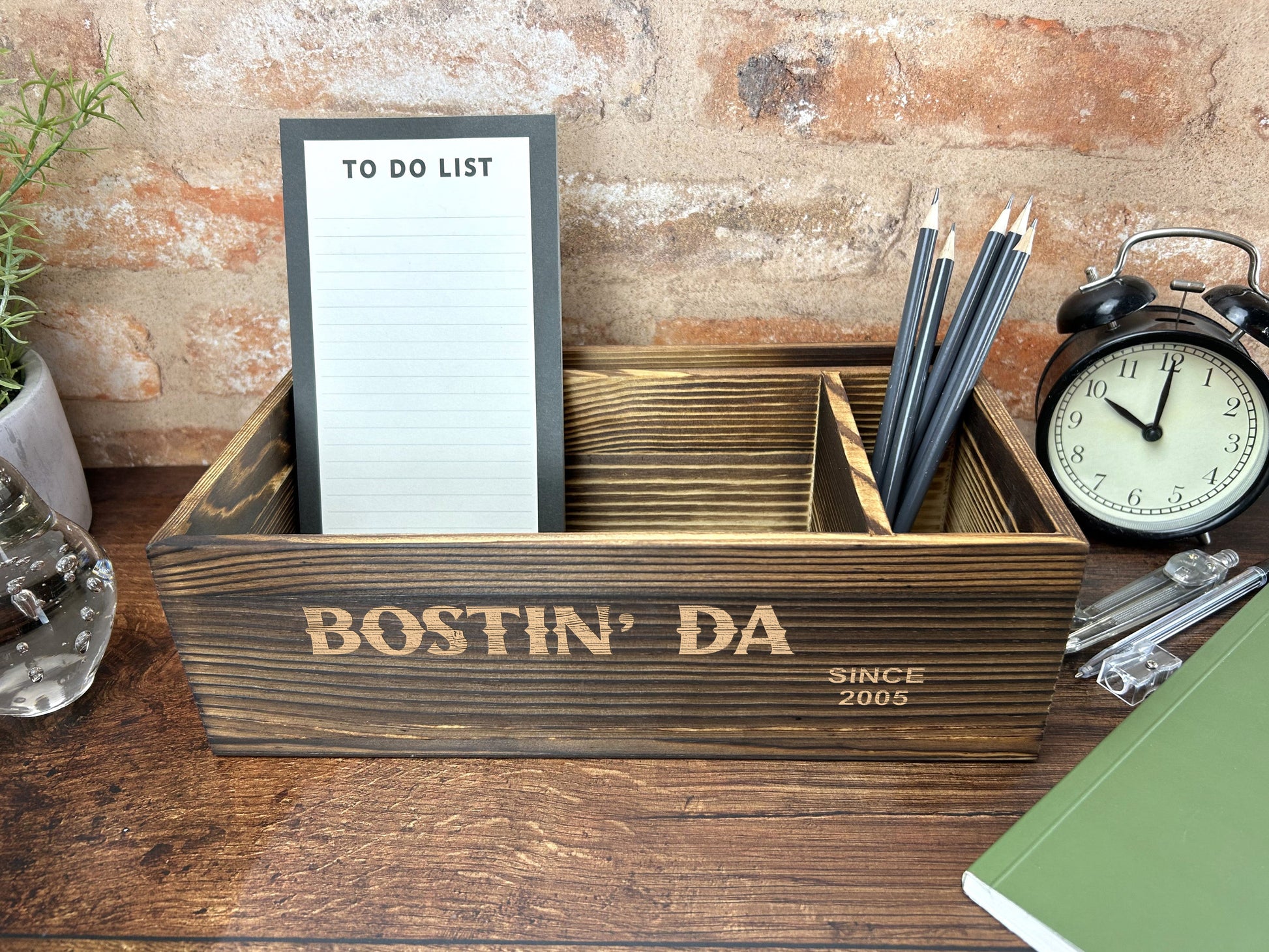 a desk with a clock, notepad and pen holder