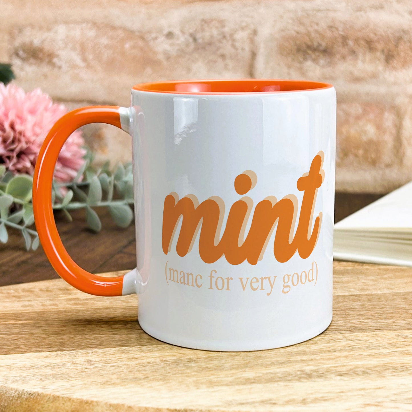 a white and orange coffee mug sitting on top of a wooden table