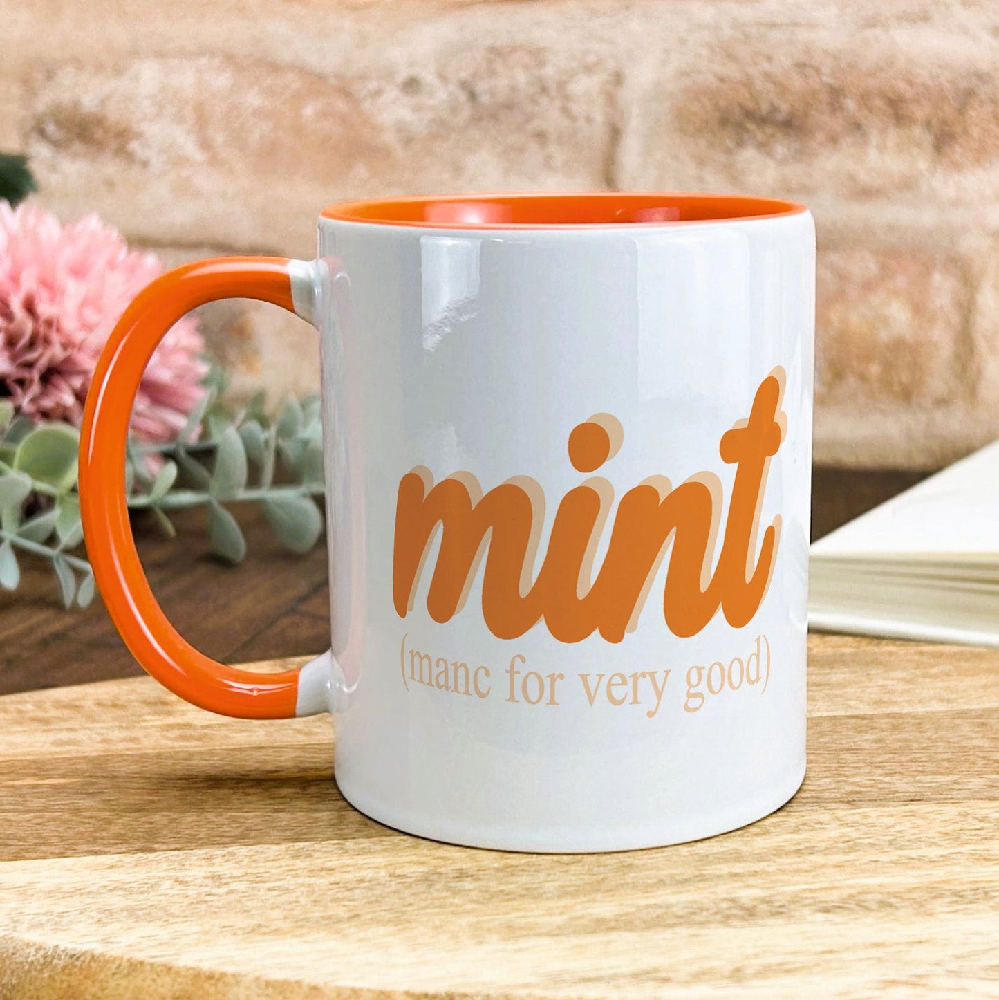a white and orange coffee mug sitting on top of a wooden table