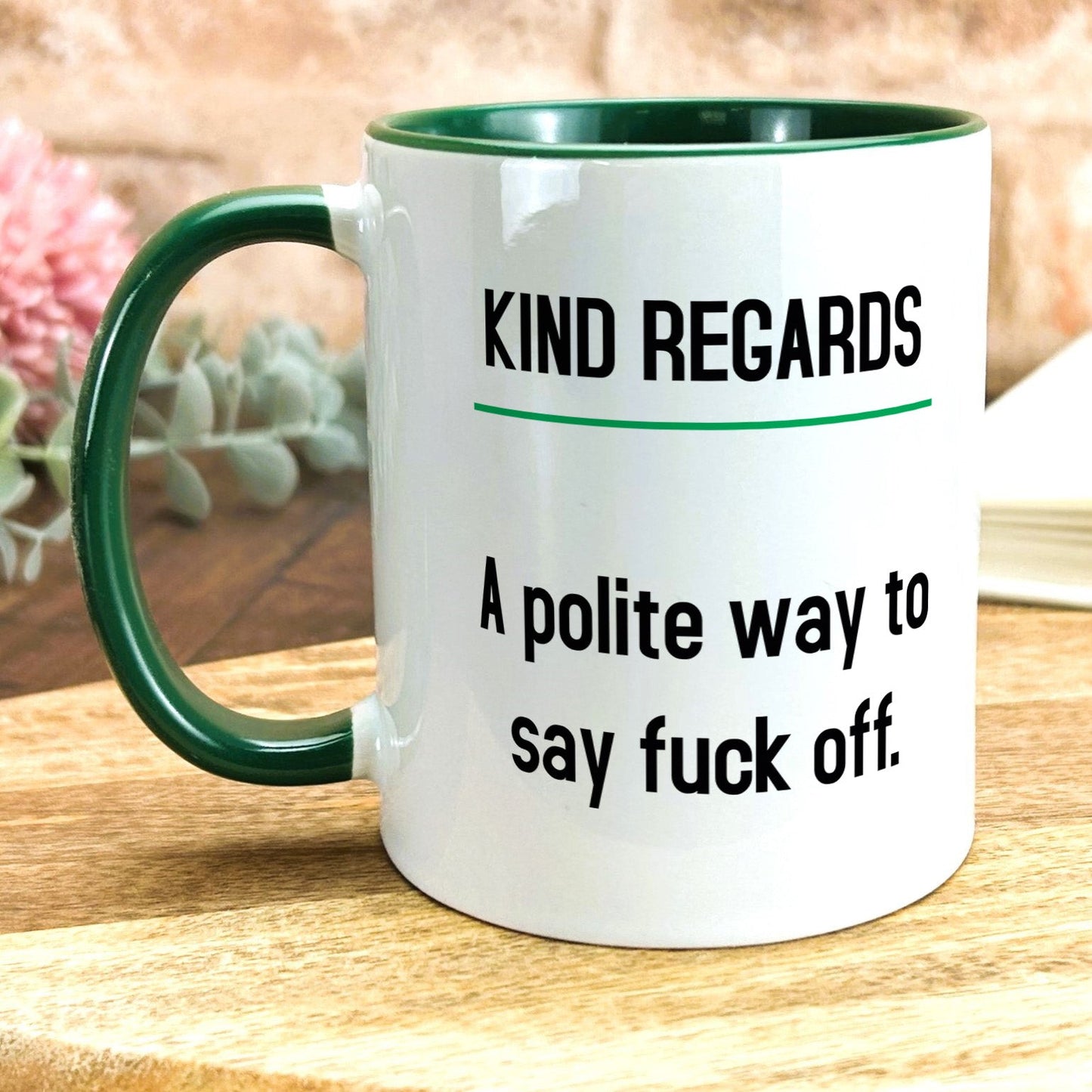 a white and green coffee mug sitting on top of a wooden table