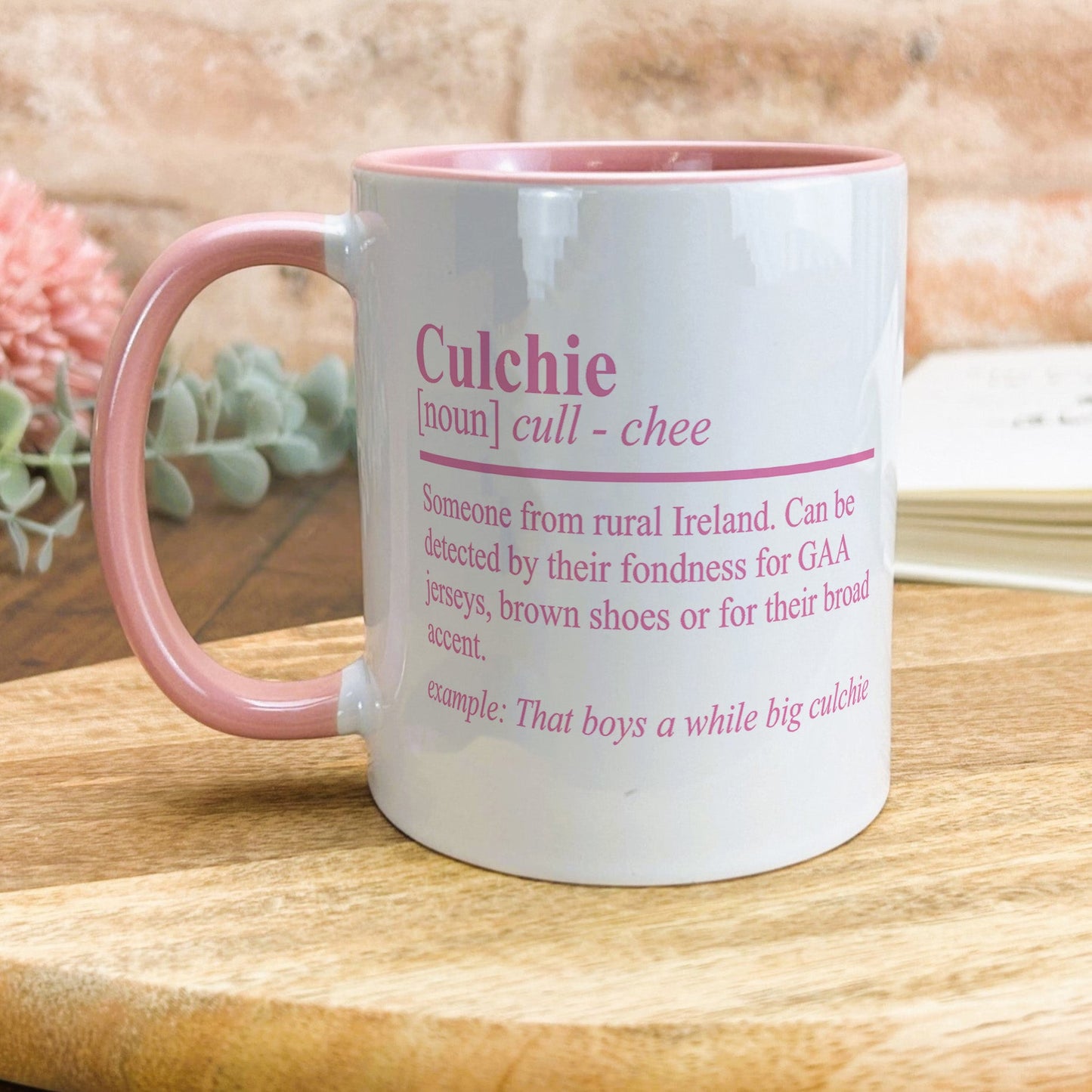 a pink and white coffee mug sitting on top of a wooden table