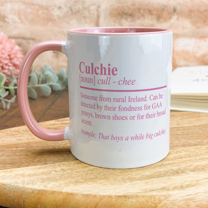 a pink and white coffee mug sitting on top of a wooden table