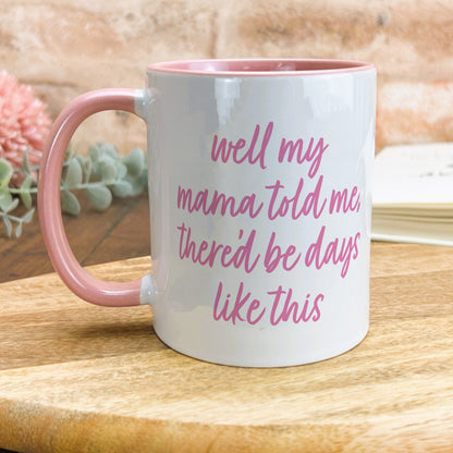 a pink and white coffee mug sitting on top of a wooden table