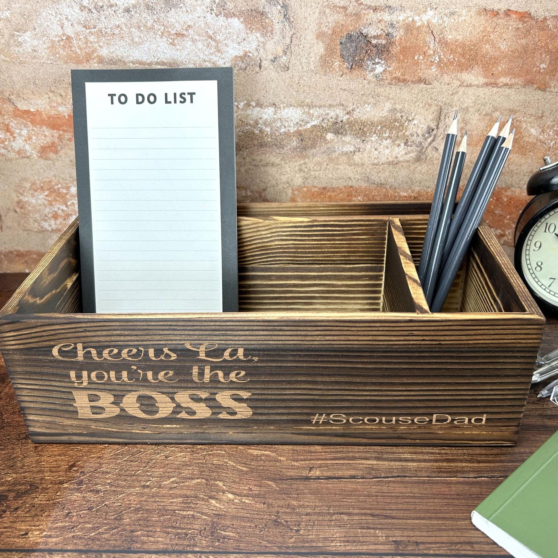 a desk with a clock, notepad and pen holder