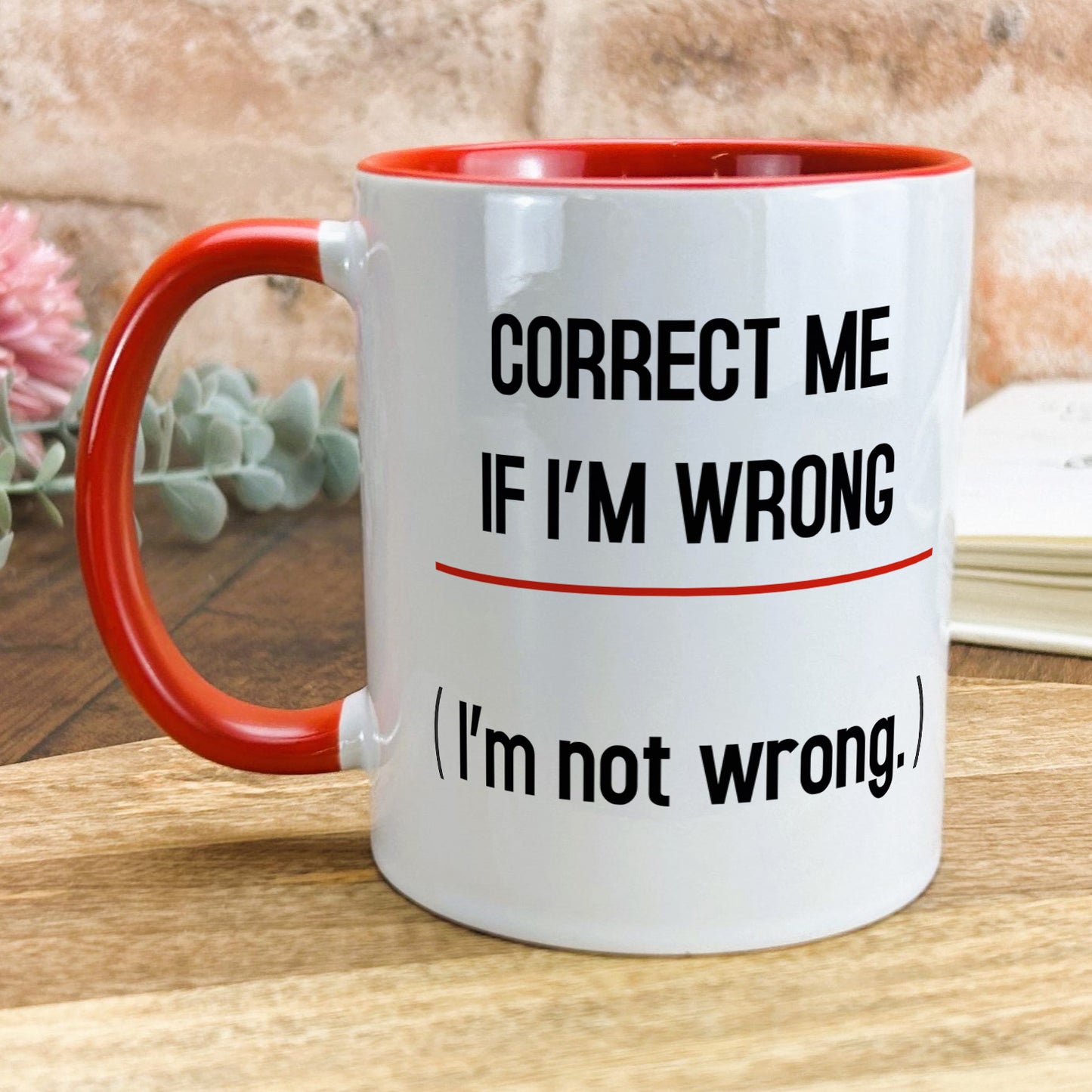 a red and white coffee mug sitting on top of a wooden table