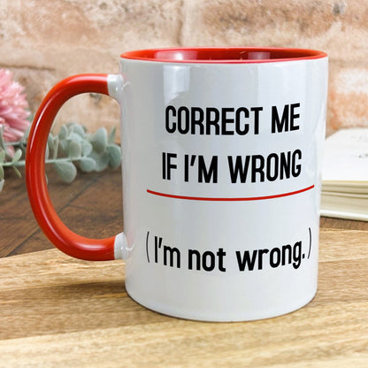 a red and white coffee mug sitting on top of a wooden table