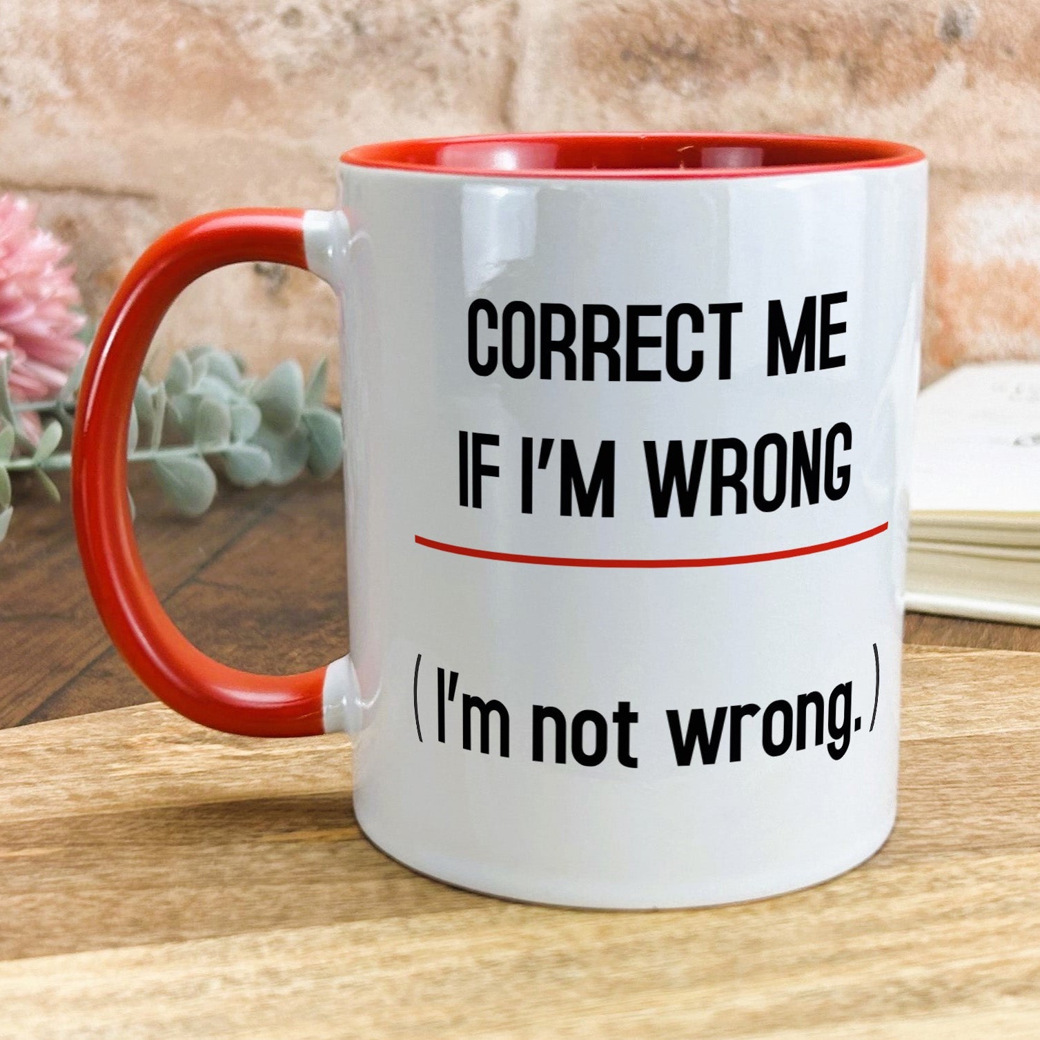 a red and white coffee mug sitting on top of a wooden table