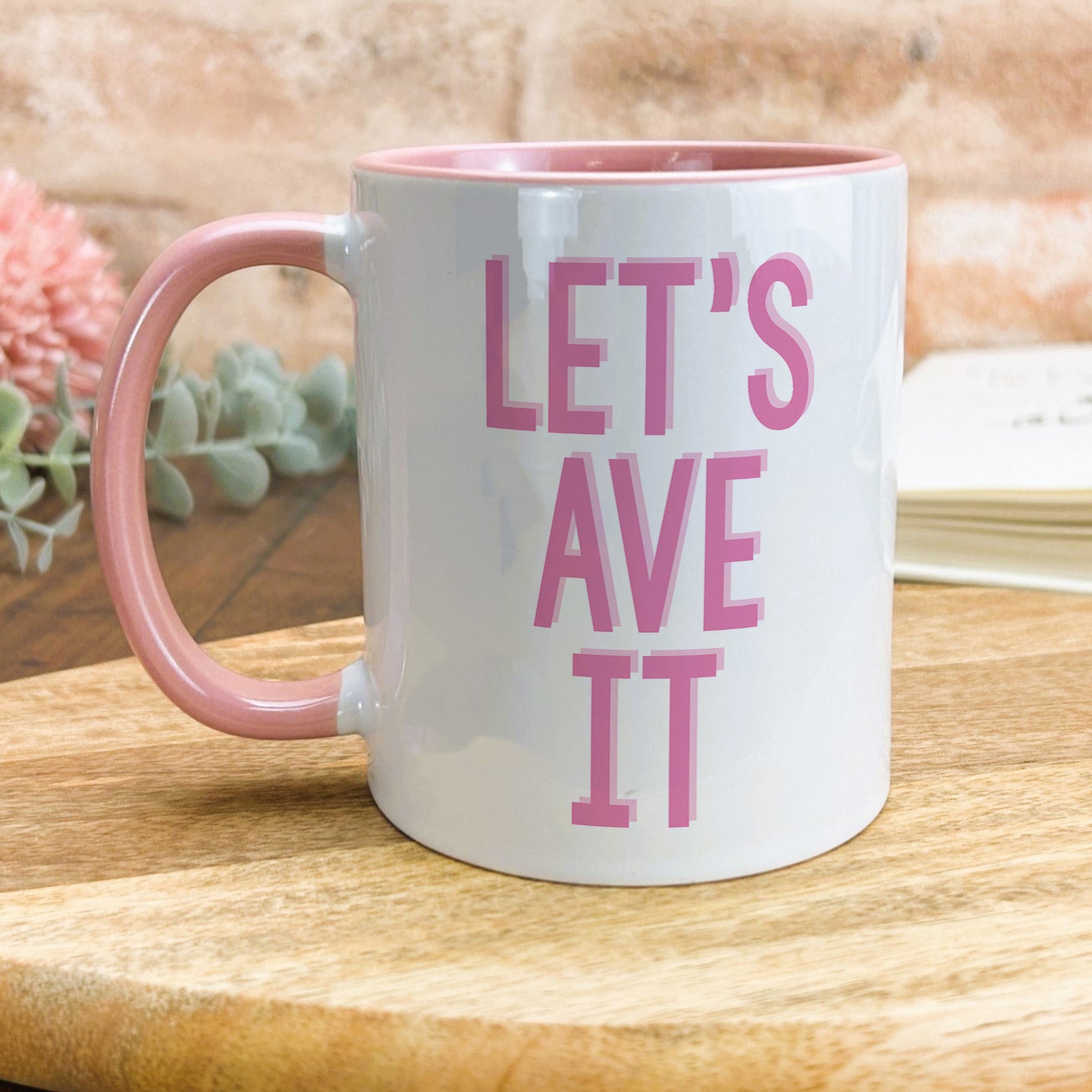 a pink and white coffee mug sitting on top of a wooden table