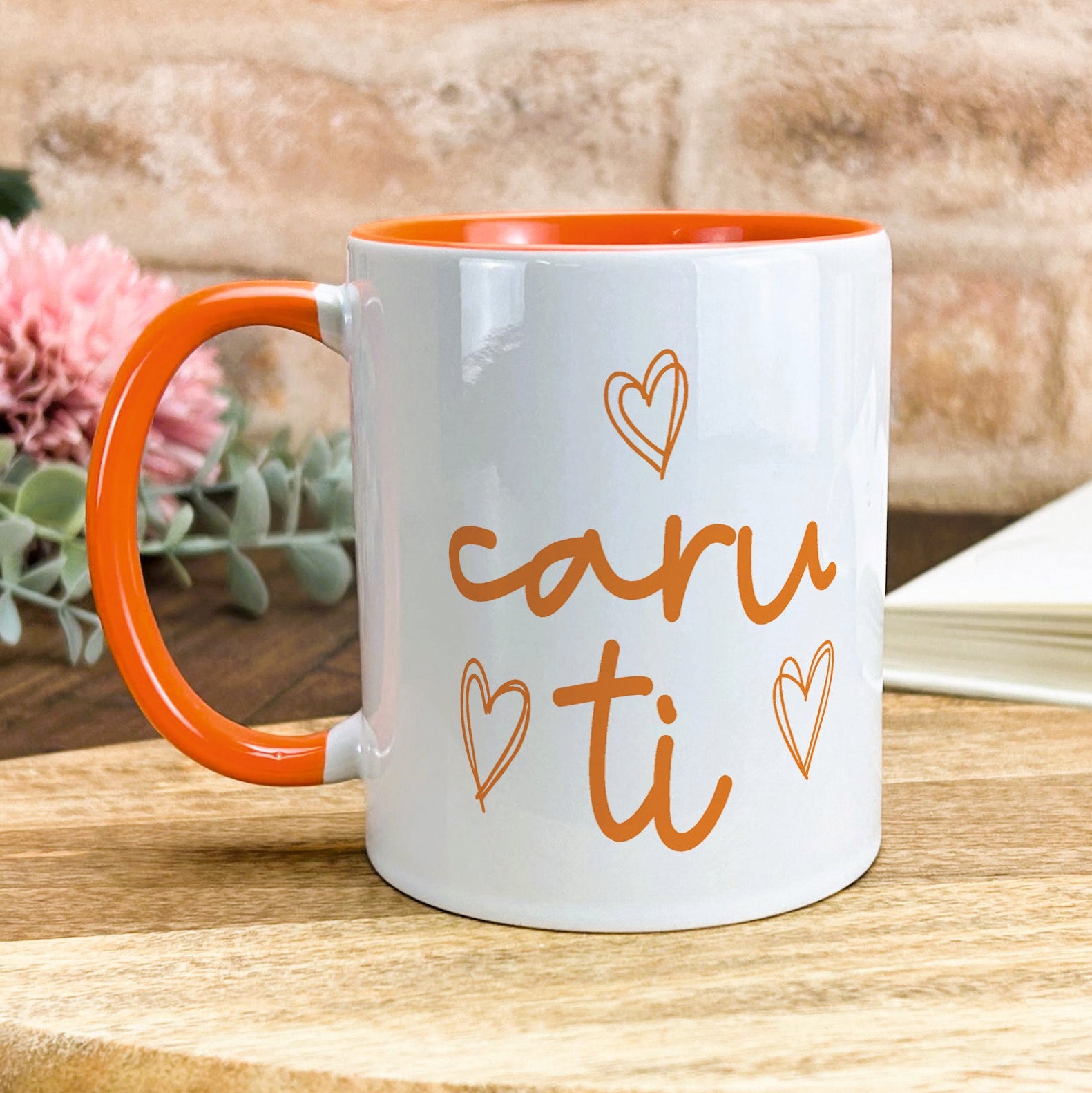 a white and orange coffee mug sitting on top of a wooden table