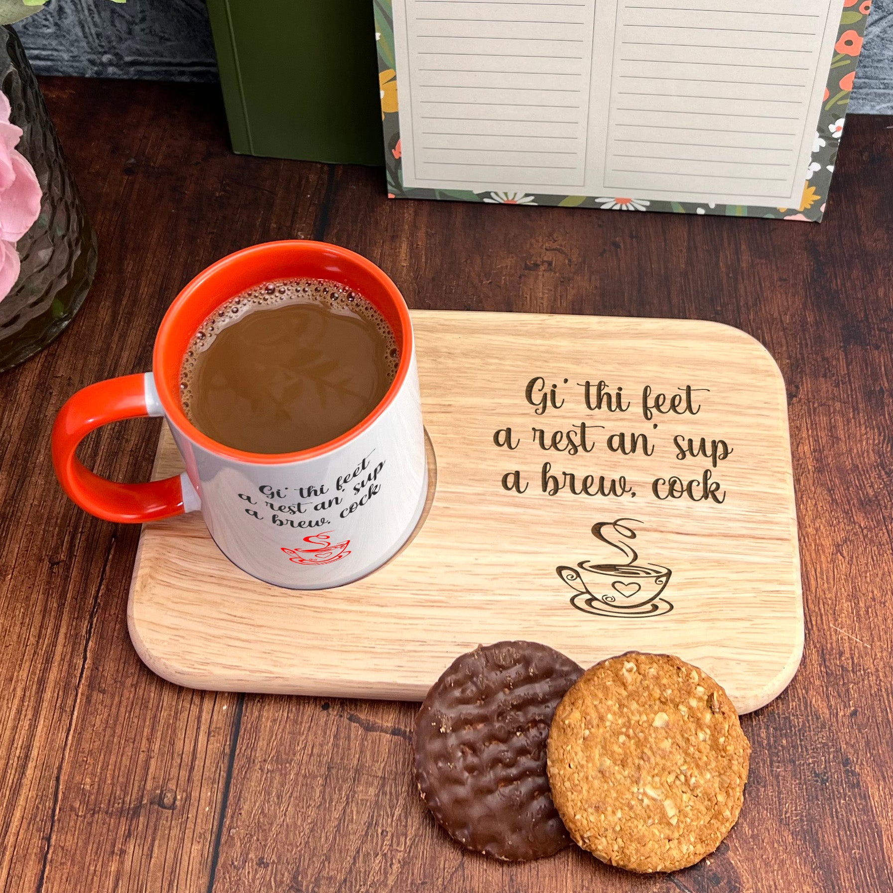 A wooden tray with a mug of coffee and two cookies, accompanied by a note that reads " Gi' thi feet a rest an sup a brew, cock".