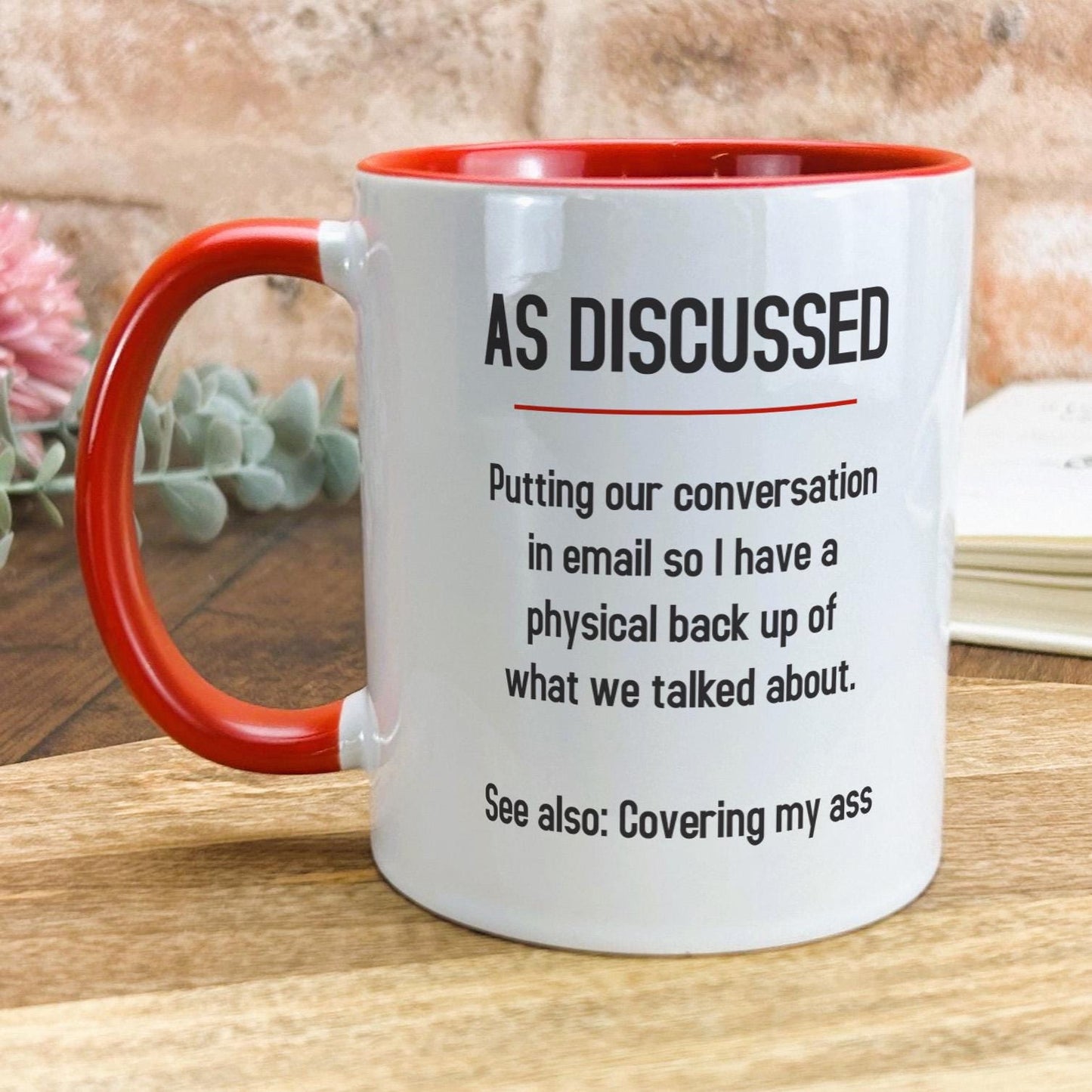 a red and white coffee mug sitting on top of a wooden table
