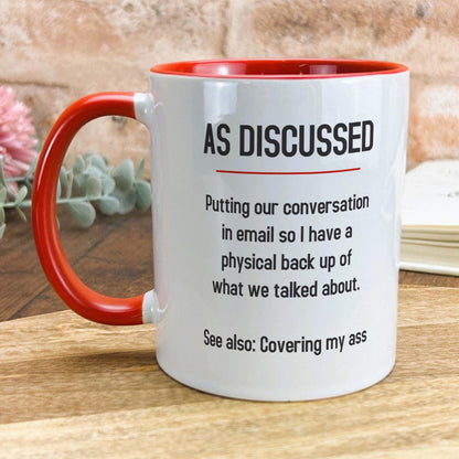 a red and white coffee mug sitting on top of a wooden table
