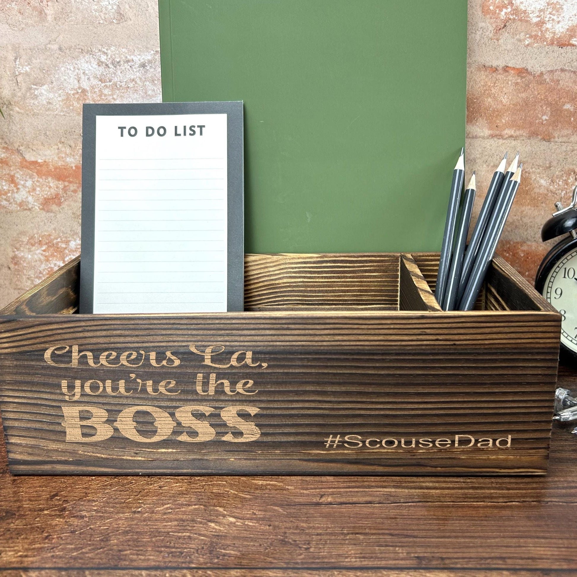 a desk with a clock, notepad and pen holder