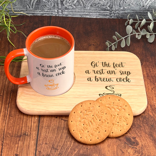 A wooden tray with a mug of coffee and two cookies on it, accompanied by a plant and some greenery.