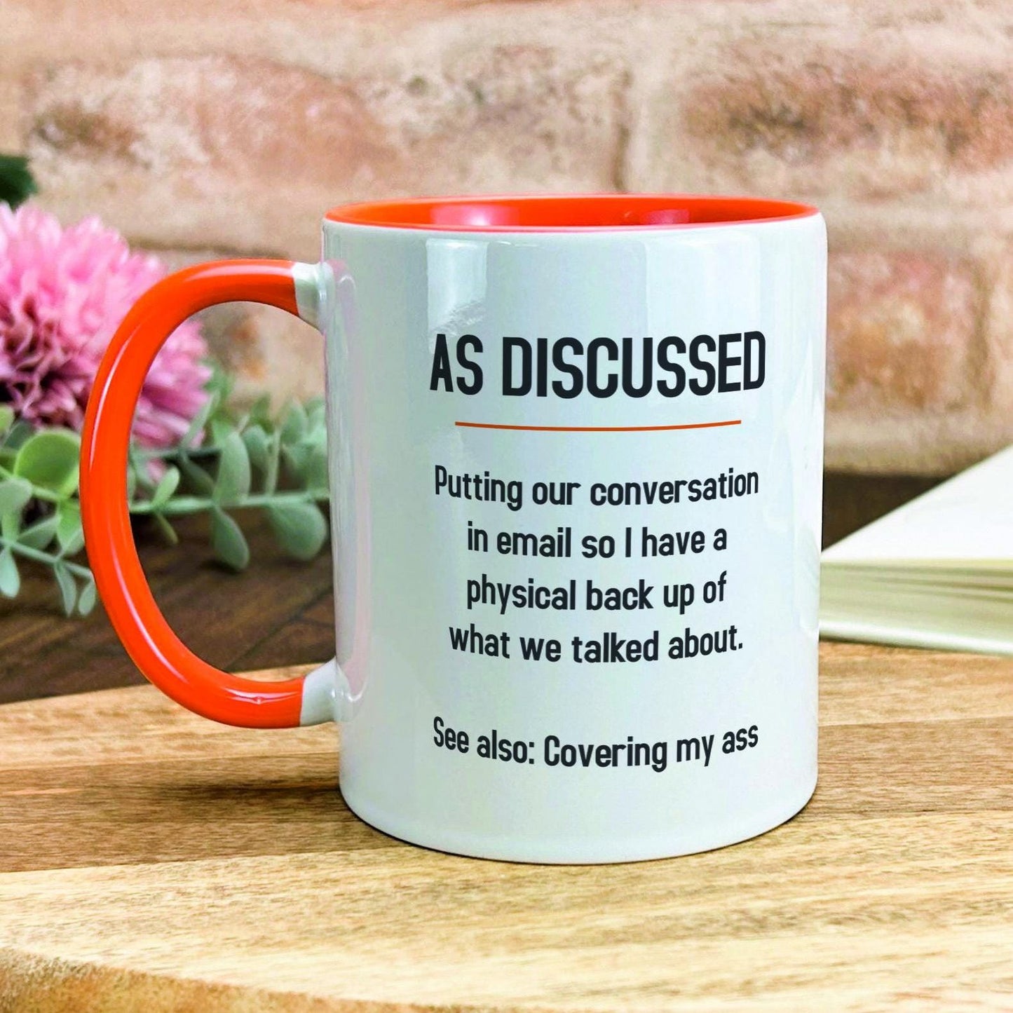 a white and orange coffee mug sitting on top of a wooden table