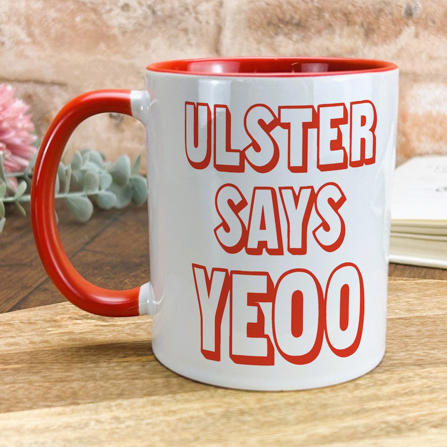 a red and white coffee mug sitting on top of a wooden table