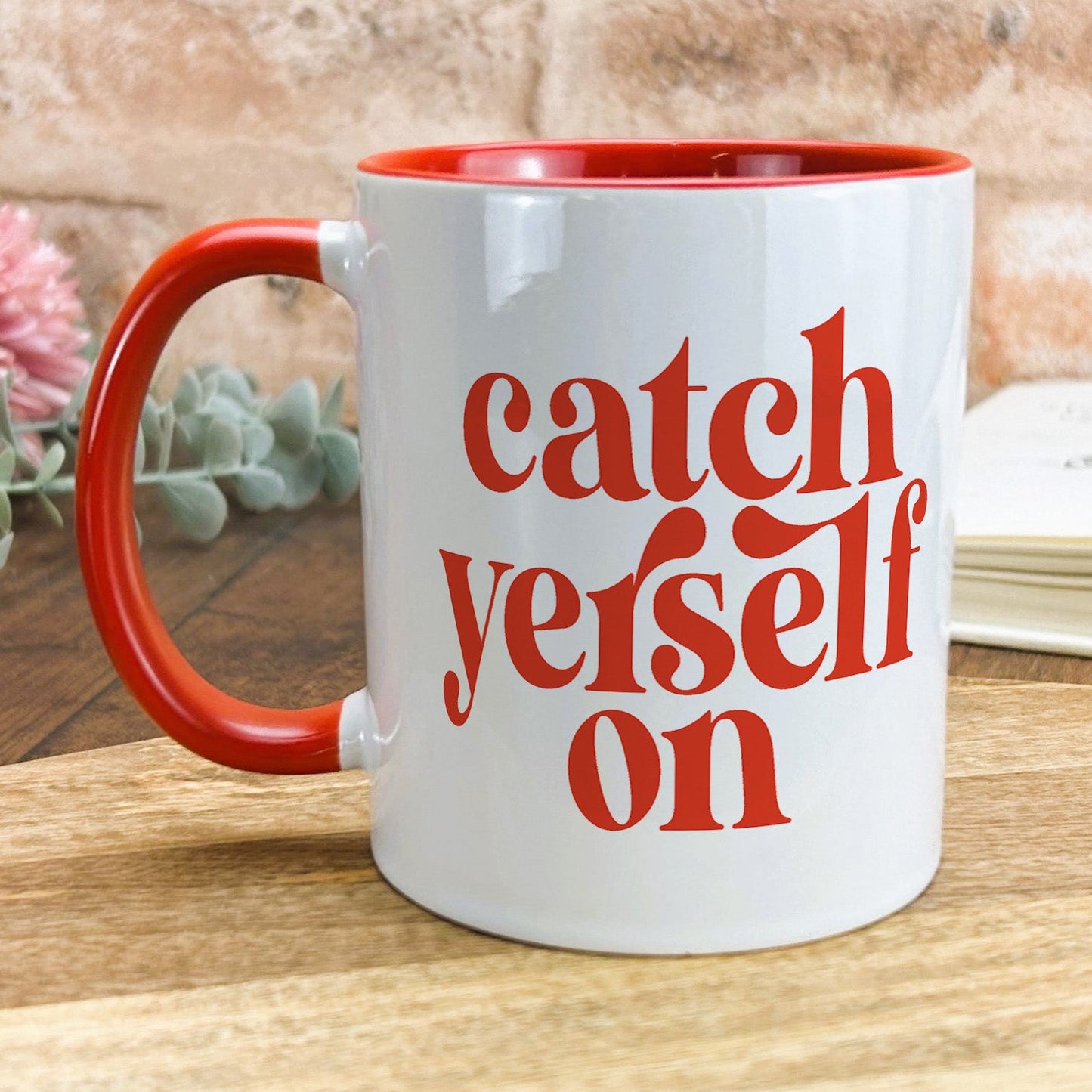 a red and white coffee mug sitting on top of a wooden table