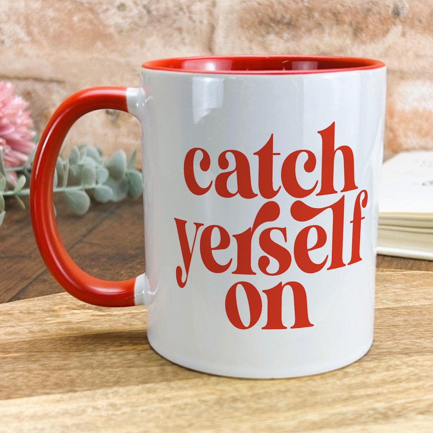 a red and white coffee mug sitting on top of a wooden table