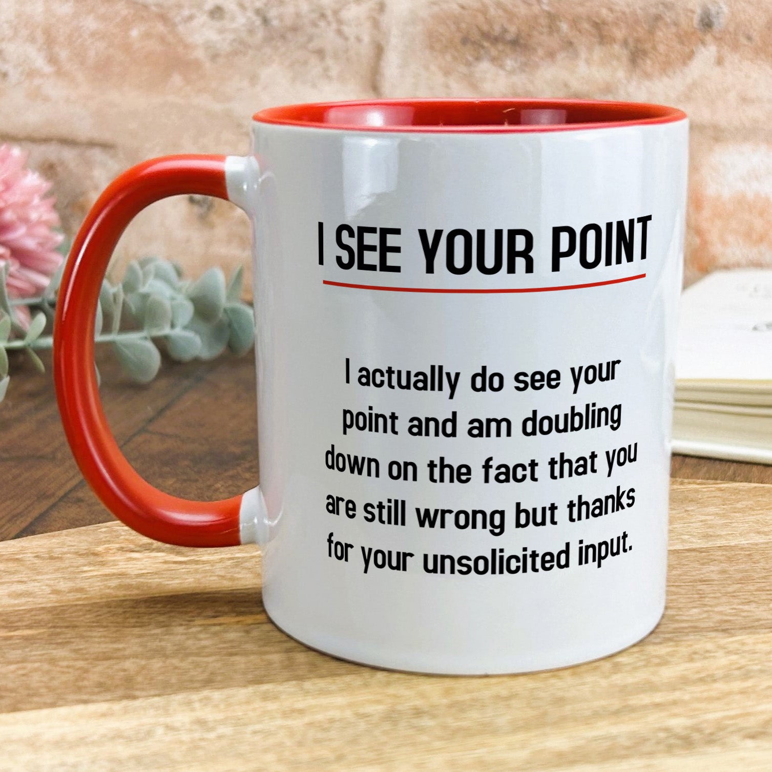 a red and white coffee mug sitting on top of a wooden table
