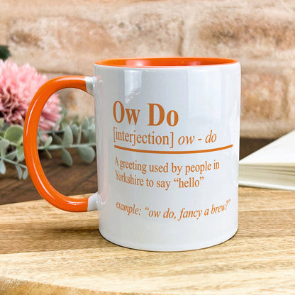 a white and orange coffee mug sitting on top of a wooden table