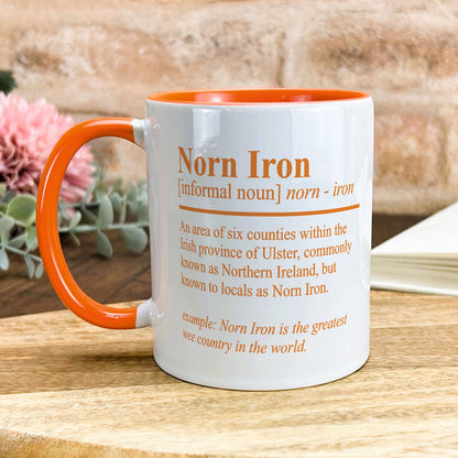 an orange and white coffee mug sitting on top of a wooden table