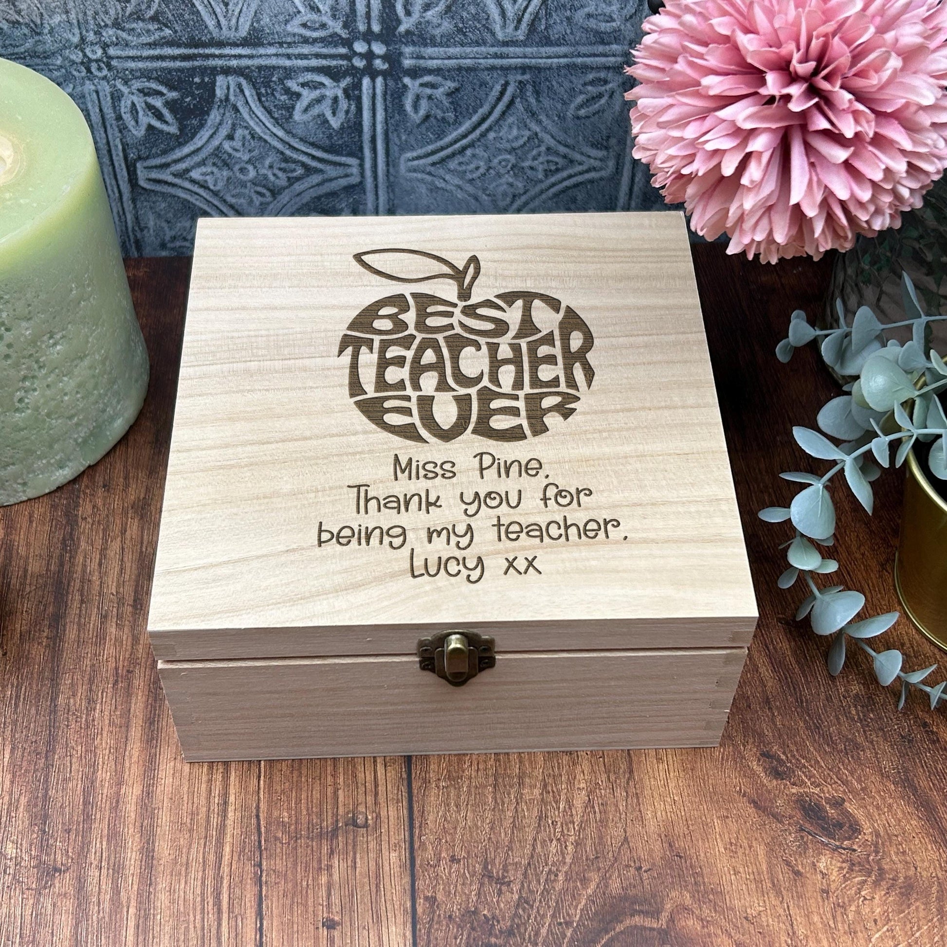 a wooden box sitting on a table next to a candle