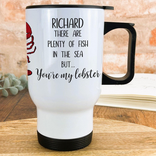 A white travel mug with a black handle, featuring a red lobster and text that reads "RICHARD THERE ARE PLENTY OF FISH IN THE SEA BUT... You're my lobster".