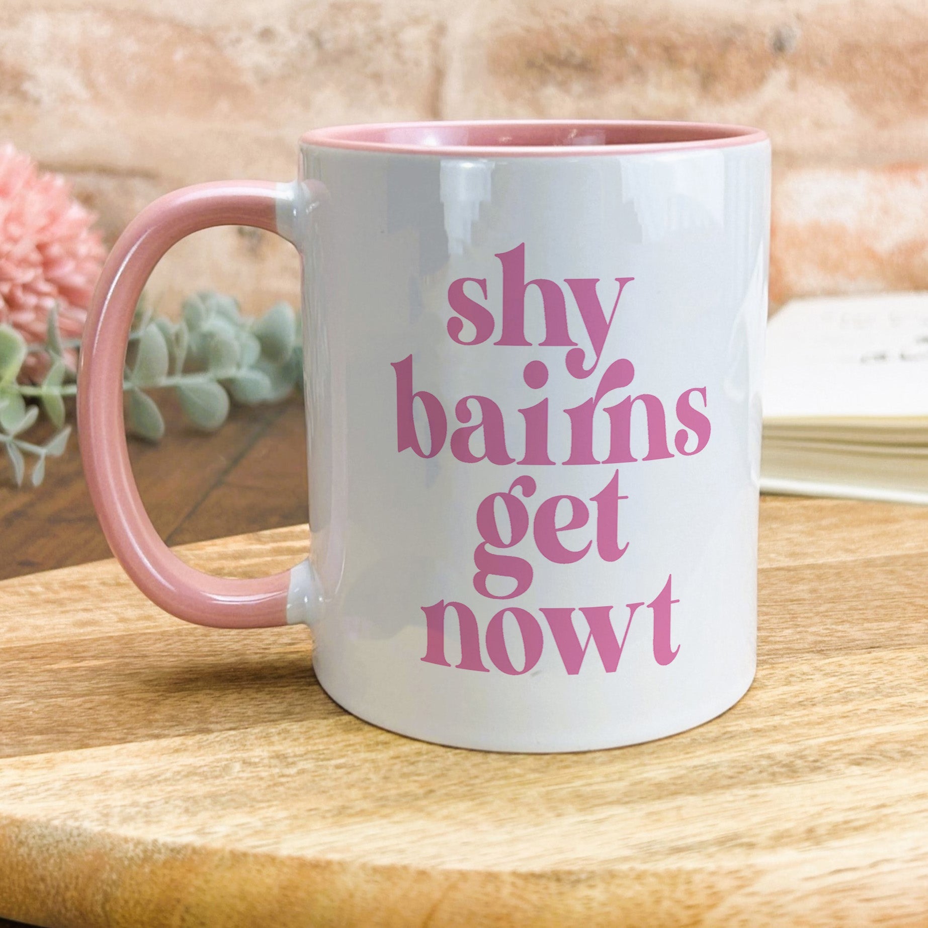 a pink and white mug sitting on top of a wooden table