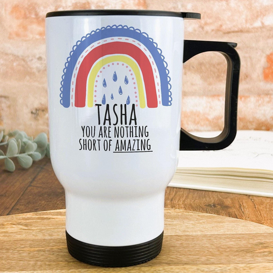 A white travel mug with a black handle, featuring a colorful rainbow design and the text "Tasha, you are nothing short of amazing" printed on it.