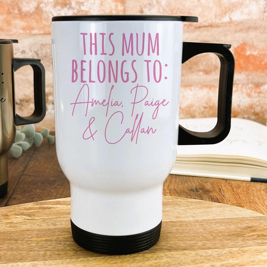 A white travel mug with text printed on it, placed on a wooden surface.